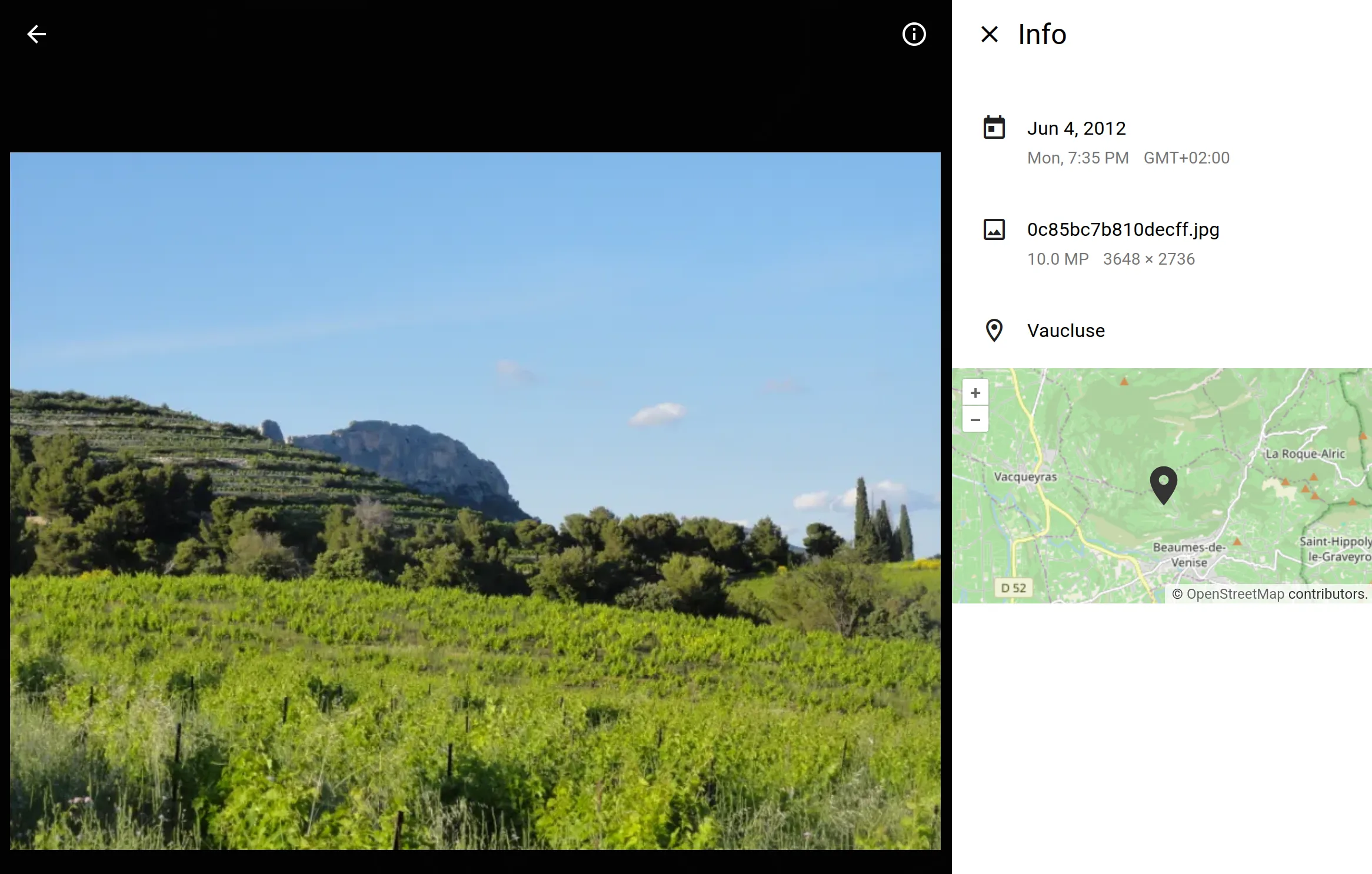 A view showing a photo of a mountain landscape with a clear blue sky. The photo is displayed in a dark-themed interface with an info panel overlayed on it.